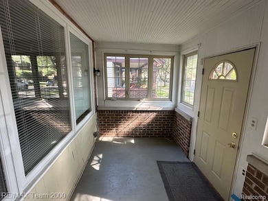 Unfurnished sunroom featuring unfinished concrete flooring and brick wall