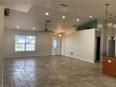 Unfurnished living room with stone tile floors, baseboards, recessed lighting, ceiling fan, and a chandelier