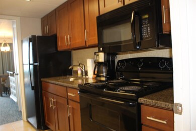 Kitchen featuring black appliances, backsplash, brown cabinets, and dark stone counters
