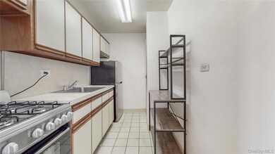 Kitchen with appliances with stainless steel finishes, light countertops, light tile patterned floors, white cabinetry, and backsplash
