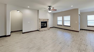 Unfurnished living room with ceiling fan, a fireplace, arched walkways, baseboards, and recessed lighting