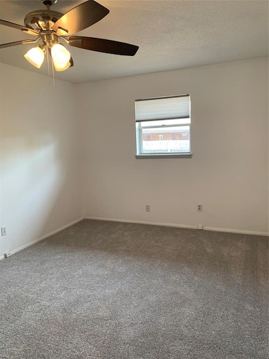 Carpeted empty room featuring a textured ceiling and ceiling fan