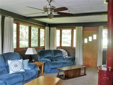 The Family Room is surrounded by windows on three sides, opens to the front of the house, and has a ceiling fan and gas heater.