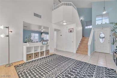 Foyer entrance featuring a high ceiling, light tile patterned flooring, ceiling fan, and stairway