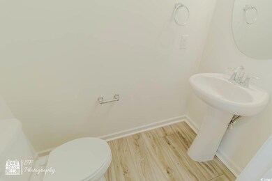 Half bathroom with toilet, wood finished floors, and baseboards