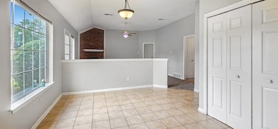Empty room with light tile patterned floors, ceiling fan, lofted ceiling, and baseboards