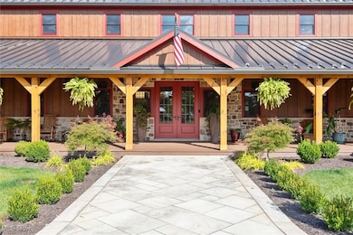 Entrance to property featuring stone siding, a standing seam roof, a metal roof, a porch, and french doors