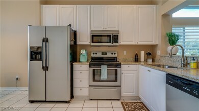 Kitchen featuring a sink, white cabinets, light ti