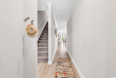Hallway featuring light wood finished floors, ornamental molding, stairs, and baseboards