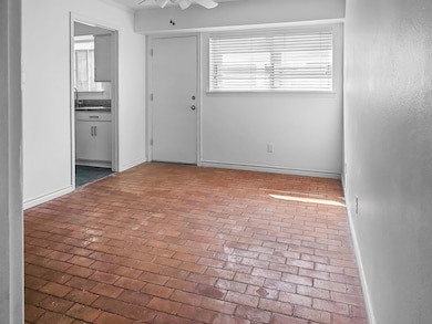 Spare room with ceiling fan, brick floor, and base