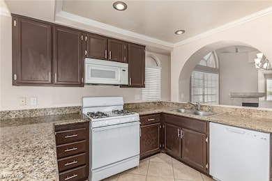 Kitchen featuring white appliances, a sink, light