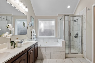Full bath featuring a bath, double vanity, light tile patterned flooring, ornamental molding, and a shower stall