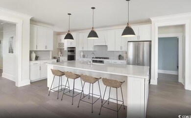 Kitchen with appliances with stainless steel finishes, dark wood finished floors, white cabinetry, and light countertops