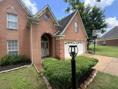 Traditional-style house featuring a front lawn, brick siding, driveway, and a garage