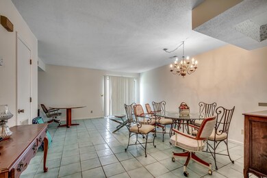 Tiled dining area with a textured ceiling, a chandelier, and baseboards