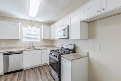 Kitchen featuring a textured ceiling, light wood-s