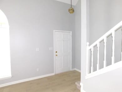 Foyer entrance featuring wood finished floors, arched walkways, stairway, and a high ceiling