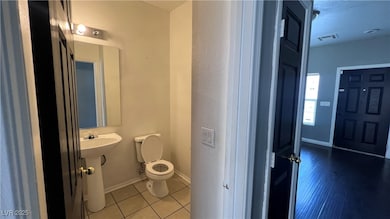 Half bathroom with toilet, baseboards, and tile pa