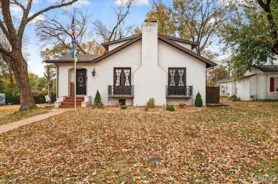 View of front of property featuring a chimney, french doors, and brick siding