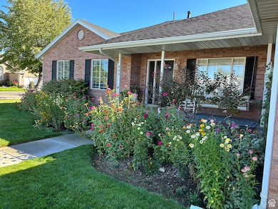 View of front facade featuring a shingled roof, a front lawn, a porch, and brick siding