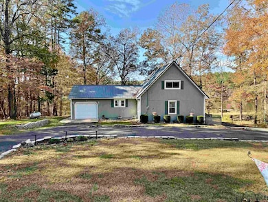 View of front of house with a front lawn, a metal roof, asphalt driveway, and a garage