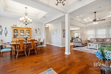 Dining area featuring hard wood-style flooring, tray ceiling, crown molding, and ornate columns
