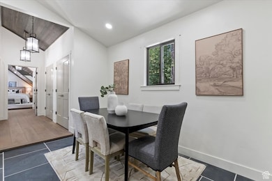 Dining space with vaulted ceiling, tile patterned flooring, and recessed lighting
