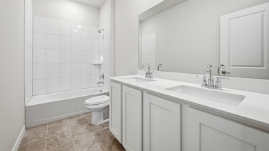 Full bathroom with shower / bath combination, double vanity, and light tile patterned flooring