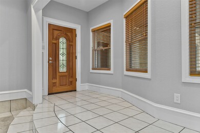 A painted wood front door with leaded glass detailing opens from the gated courtyard into an inviting foyer where you'll notice recent interior paint with oversized 9-inch baseboards, recessed lighting, and easy maintenance tile flooring.