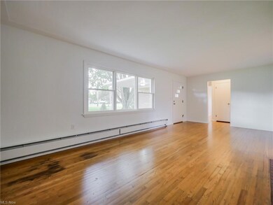 Wood floored empty room with a baseboard radiator