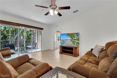 Living area with lofted ceiling, a ceiling fan, and light tile patterned floors