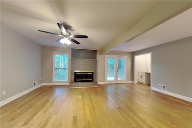 Unfurnished living room with ceiling fan, healthy amount of natural light, a fireplace, and light wood-type flooring