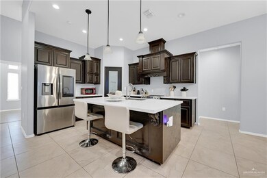 Kitchen with light countertops, visible vents, dark brown cabinets, a sink, and stainless steel refrigerator with ice dispenser