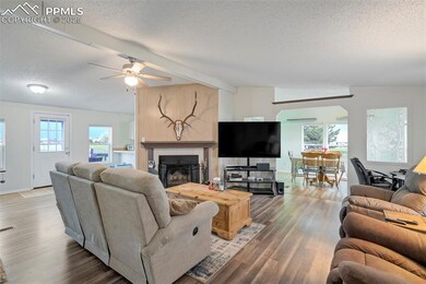 Living room with a textured ceiling, ceiling fan, wood finished floors, a fireplace, and arched walkways