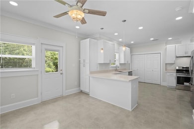 Kitchen with stainless steel range with electric stovetop, a sink, plenty of natural light, ornamental molding, and light countertops