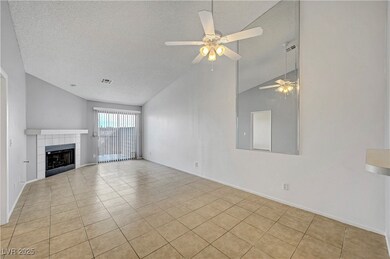 Unfurnished living room with a textured ceiling, light tile patterned flooring, a fireplace, a ceiling fan, and high vaulted ceiling