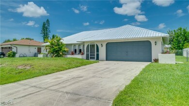 View of front facade featuring stucco siding, a garage, driveway, and a metal roof