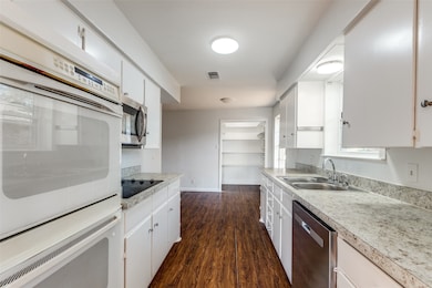 Kitchen featuring appliances with stainless steel finishes, dark wood-style floors, light countertops, and white cabinetry