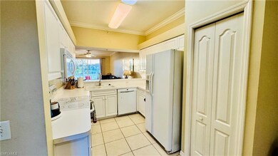 Kitchen featuring white appliances, ornamental molding, white cabinetry, light countertops, and light tile patterned floors