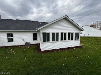 Back of house with a lawn, a sunroom, and roof with shingles