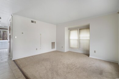 Spare room with crown molding, light colored carpet, visible vents, and baseboards