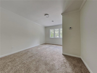 Carpeted empty room featuring ornamental molding and baseboards