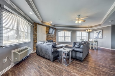 Living room with dark hardwood / wood-style flooring, ornamental molding, a raised ceiling, and a wall mounted air conditioner