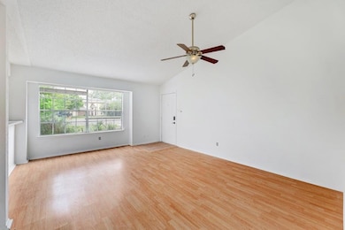Unfurnished room featuring light wood-type flooring, lofted ceiling, ceiling fan, and a textured ceiling