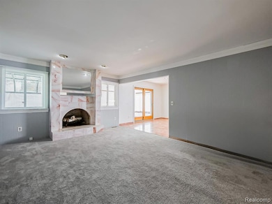 Unfurnished living room with a tiled fireplace, carpet flooring, french doors, and crown molding