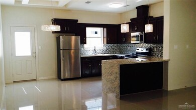 Kitchen featuring stainless steel appliances, light tile patterned floors, backsplash, light stone counters, and a peninsula