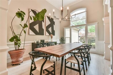 Dining room featuring crown molding, a wainscoted wall, light wood finished floors, ornate columns, and a decorative wall