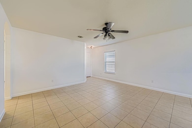 Empty room featuring light tile patterned flooring and a ceiling fan
