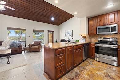 Kitchen with vaulted ceiling, open floor plan, stainless steel appliances.
