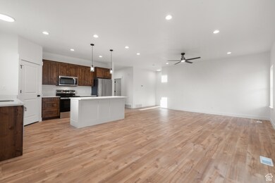 Kitchen featuring stainless steel appliances, pendant lighting, a center island, recessed lighting, and light wood-type flooring